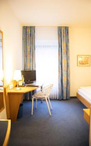 a room with a desk with a computer and a bed at Park Hotel in Schweinfurt