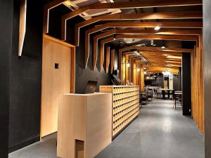 a restaurant with wooden ceilings and a long hallway with tables at Namba Guesthouse HIVE in Osaka