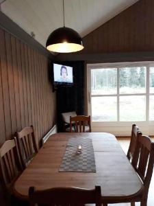 a dining room with a wooden table and a television at 14-Nasjonalpark, sykling, fisking, kanopadling, skogs- og fjellturer in Trysil