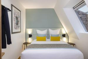 1 dormitorio con 1 cama con 2 almohadas amarillas en Hôtel Du Dragon, en Estrasburgo