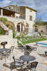 eine Terrasse mit Tischen und Stühlen vor einem Gebäude in der Unterkunft MAS COURADOU in Labastide-de-Virac