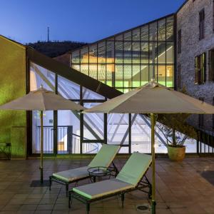 - deux chaises et des parasols sur une terrasse en face d'un bâtiment dans l'établissement Parador De La Seu D'urgell, à La Seu d'Urgell