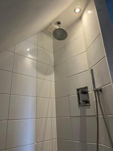 y baño con ducha y pared de azulejos blancos. en Torenzicht, en Kapelle