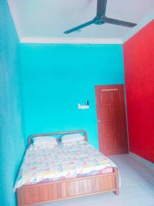 um quarto com uma cama com uma parede azul e vermelha em Sobey Laris Homestay KAYDEE em Pasir Mas