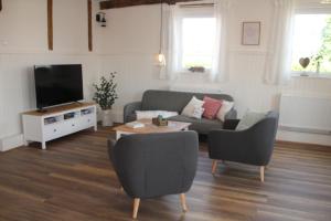 a living room with a couch and a tv at Ferienwohnung - Zur alten Wirtsstube in Unterleichtersbach