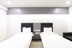 2 Betten in einem Zimmer mit weißen Wänden in der Unterkunft Alba Premier, Ahmedabad in Ahmedabad