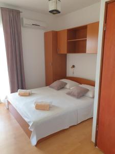 1 dormitorio con 1 cama blanca y 2 almohadas en Apartments FIGA, en Orebić
