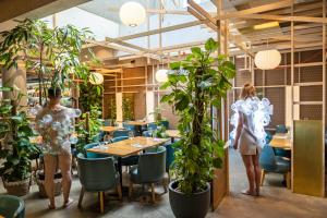 twee mensen staan in een restaurant met planten bij Nomad Design & Lifestyle Hotel in Bazel