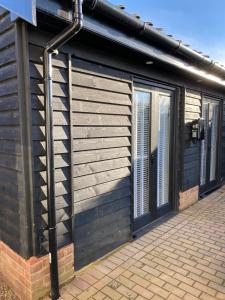 a wooden building with doors and windows on it at The Pelican Room-converted Cart Lodge near airport in Horsham Saint Faith