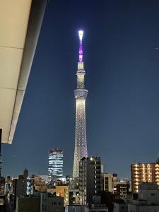 una torre alta illuminata di notte in una città di ASAKUSAーHANAKAWADO a Tokyo
