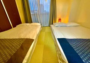 two beds sitting in a room with a window at Love Asakusa 1 Bedroom Apartment Sleeps 6 SkyTree View 3 Min to Sensoji Airport Direct Elevator Free WiFi in Tokyo