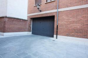 アビラにあるCasa El Paradorの黒いガレージドアとレンガ造りの建物を備えたガレージ