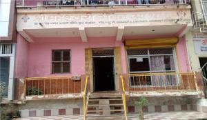 ein rosafarbenes Gebäude mit einer Tür und einem Balkon in der Unterkunft Maheshwari Bhavan By WB Inn in Sītāpur Mūāfi