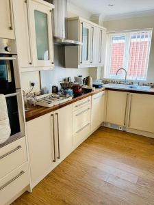 a kitchen with white cabinets and a wooden floor at Cosy 3-bed house in Hull