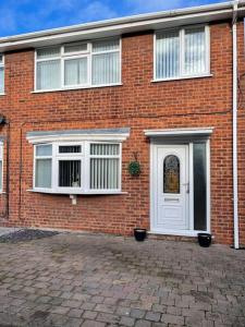 a brick house with a white door and windows at Cosy 3-bed house in Hull