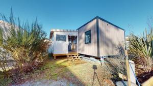 una pequeña casa gris con una puerta en un patio en Mobil home domaine avec piscine proche mer, en La Parée Preneau