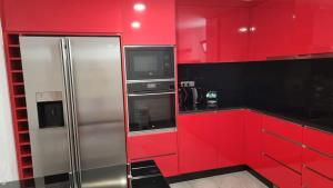 uma cozinha vermelha com um frigorífico e uma televisão em Lombada House em Ponta Delgada
