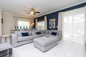 ein Wohnzimmer mit einem grauen Sofa und einem Deckenventilator in der Unterkunft Stunning 5 Bd w/ Pool Close to Disney 2905 in Kissimmee