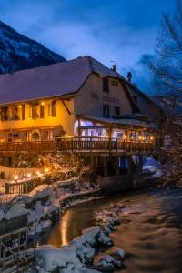 un hôtel avec un pont sur une rivière la nuit dans l'établissement Le Christiania Hotel & Spa, à La Salle Les Alpes