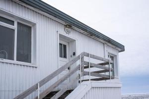 a white building with a staircase next to a door at The Holiday Houses in Kirkjubæjarklaustur