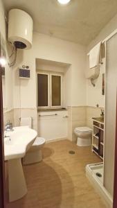 uma casa de banho com um lavatório branco e um WC. em La casa di sally em Pitigliano