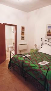 1 dormitorio con 1 cama con colcha verde en La casa di sally, en Pitigliano
