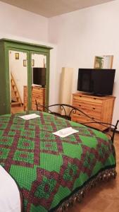 sypialnia z kołdrą na łóżku i telewizorem w obiekcie La casa di sally w mieście Pitigliano