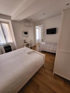 a white bedroom with two beds and a television at Affittacamere Il Timone in Corniglia