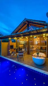 uma casa com um deque e uma piscina à noite em Chalé Arara super Luxo em Cunha
