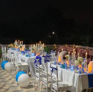 un grupo de mesas con sillas blancas y velas en Sunrise Farm استراحة مطلع الشمس en Hatta
