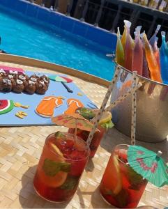 dos cócteles en una mesa junto a la piscina en Sunrise Farm استراحة مطلع الشمس en Hatta