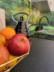 a basket of apples and oranges on a counter with a tea kettle at Apartament z antresolą in Nickelswalde