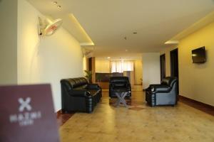 a living room with leather furniture and a tv at hazmi inn in Perintalmanna