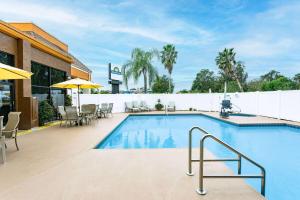 ein Pool mit Tischen und Stühlen und ein Gebäude in der Unterkunft Days Inn by Wyndham N Orlando/Casselberry in Orlando