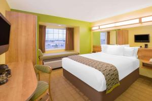 a hotel room with a large bed and a television at Microtel Inn & Suites by Wyndham Delphos in Delphos