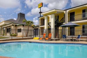 a pool in front of a hotel with chairs and an umbrella at Super 8 by Wyndham McDonough GA in McDonough