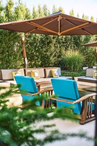 2 chaises bleues et une table sous un parasol dans l'établissement Savoy Hotel & Spa - Preferred Hotels & Resorts, à Paestum
