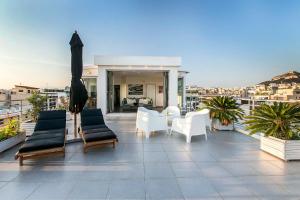 a patio with chairs and tables on a balcony at Acropolis Panorama View Penthouse with Private Terraces A Contemporary Parthenon in Athens