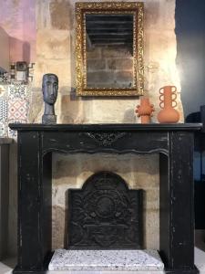 a black fireplace with a statue and a mirror at Le 6 Bis by Les Cailloux Dorés in Uzès