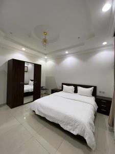 a white bedroom with a large bed and a mirror at غايا للشقق المخدومة in Tabuk