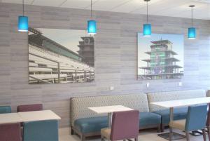 a restaurant with tables and chairs and a painting of a stadium at La Quinta Inn & Suites by Wyndham Indianapolis Downtown in Indianapolis