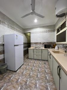 a kitchen with a white refrigerator and a sink at غايا للشقق المخدومة in Tabuk