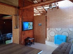 sala de estar con sofá y TV en la pared en Dunas do Moçambique, en Florianópolis