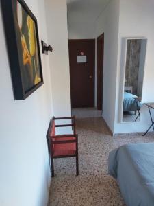 Cette chambre comprend un lit, une chaise et un miroir. dans l'établissement Hostal Tivissa, à Tivissa
