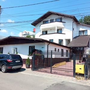 a house with a fence and a car parked in front at Pensiunea Marcello in Iaşi