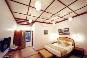 1 dormitorio con 1 cama grande y techo artesonado en Tranquil Resort & Spa, en Mahabaleshwar