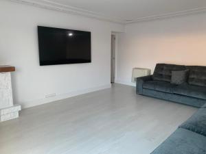 sala de estar con sofá y TV de pantalla plana en Villa Aurora en La Bañeza