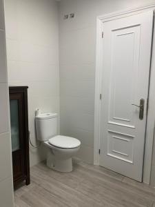 a white bathroom with a toilet and a door at Villa Aurora in La Bañeza