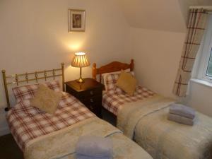 a bedroom with two beds and a lamp on a table at Abbeybank Lodge in New Abbey