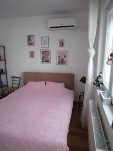 a bedroom with a pink bed and a window at Studio apartman Promenada in Sarajevo